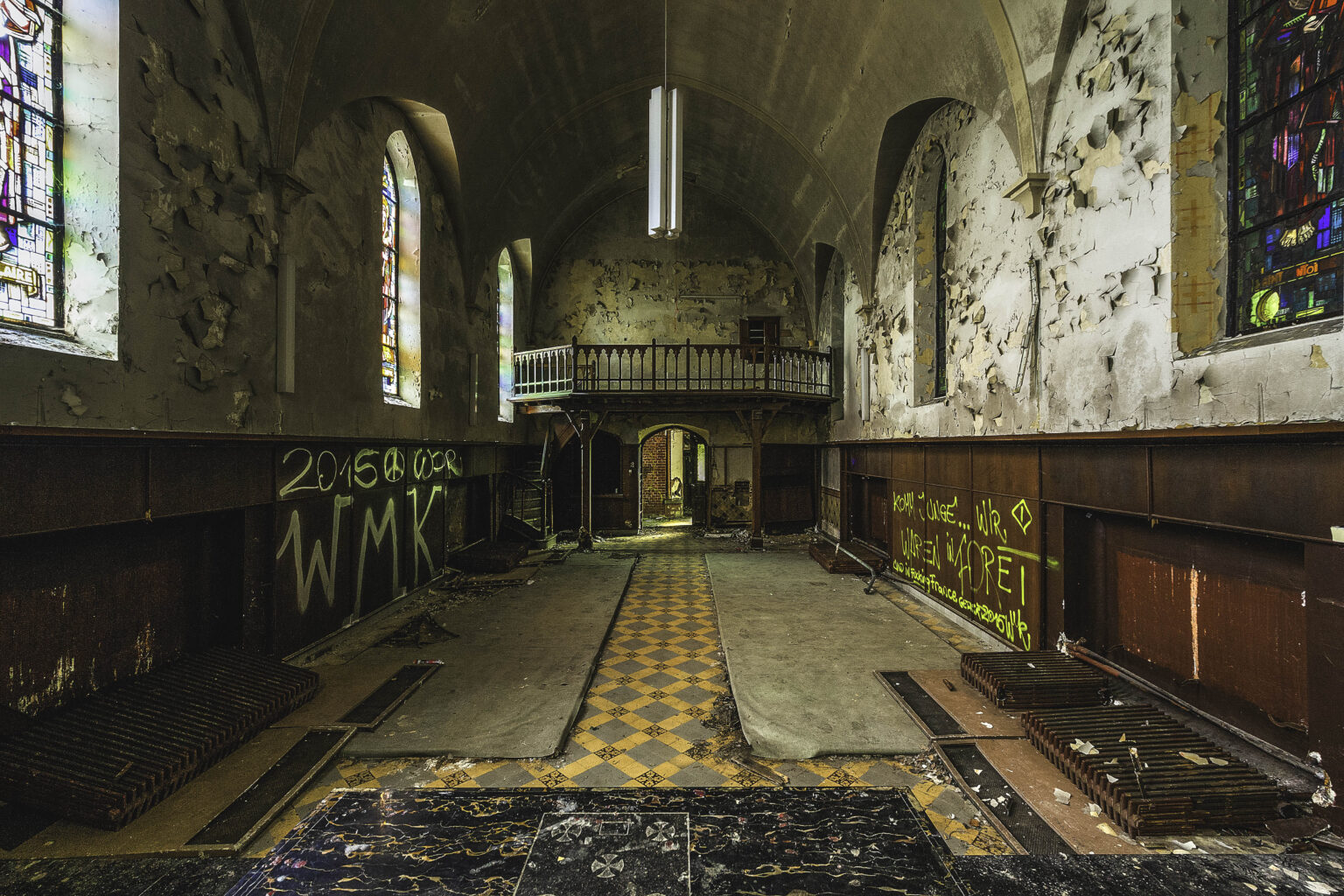 Kapellenschiff von der Empore mit Schachbrettboden und Holzvertäfelung im Lost Place