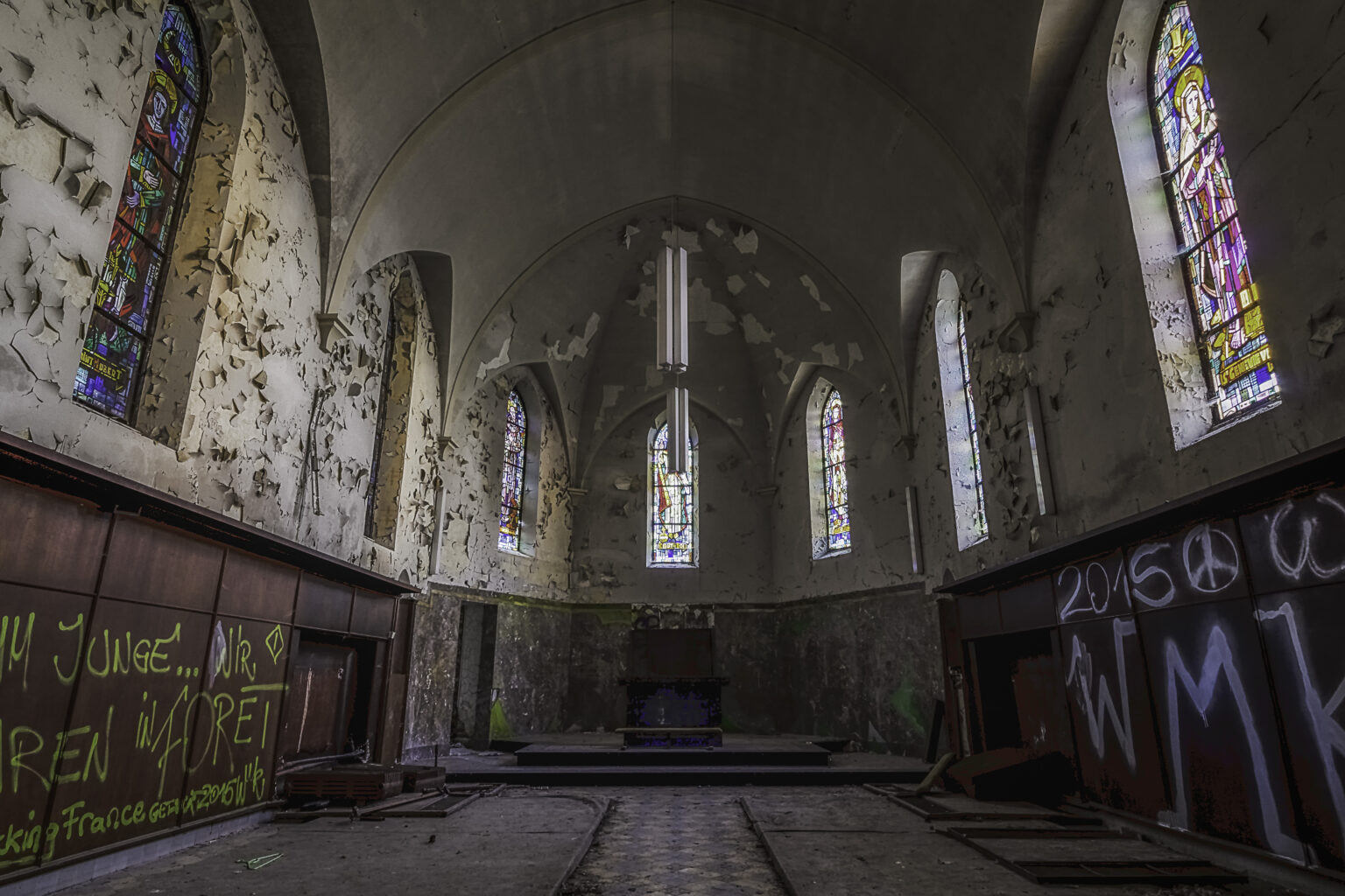 Kapellenchor mit Lanzett-Buntglasfenstern und verfallener Apsis am Altar im Lost Place