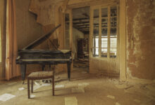Verlassenes Zimmer mit Klavier und Notenblättern.