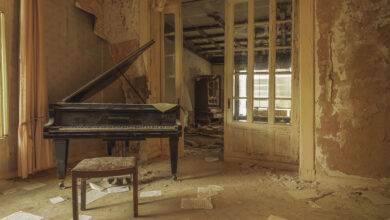 Verlassenes Zimmer mit Klavier und Notenblättern.