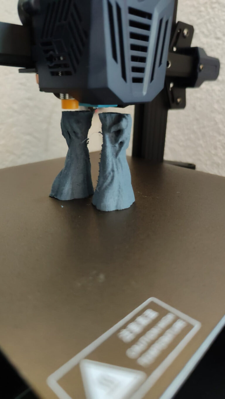 FDM-3D-Drucker druckt zwei graue Beine einer Figur auf dem Druckbett