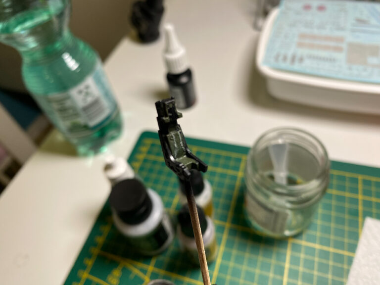 Schwarz lackiertes Cockpitteil auf einem Stäbchen über Modellbaufarben