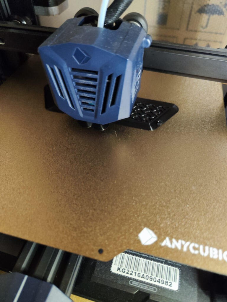Blauer Druckkopf eines Anycubic-3D-Druckers über dem Druckbett