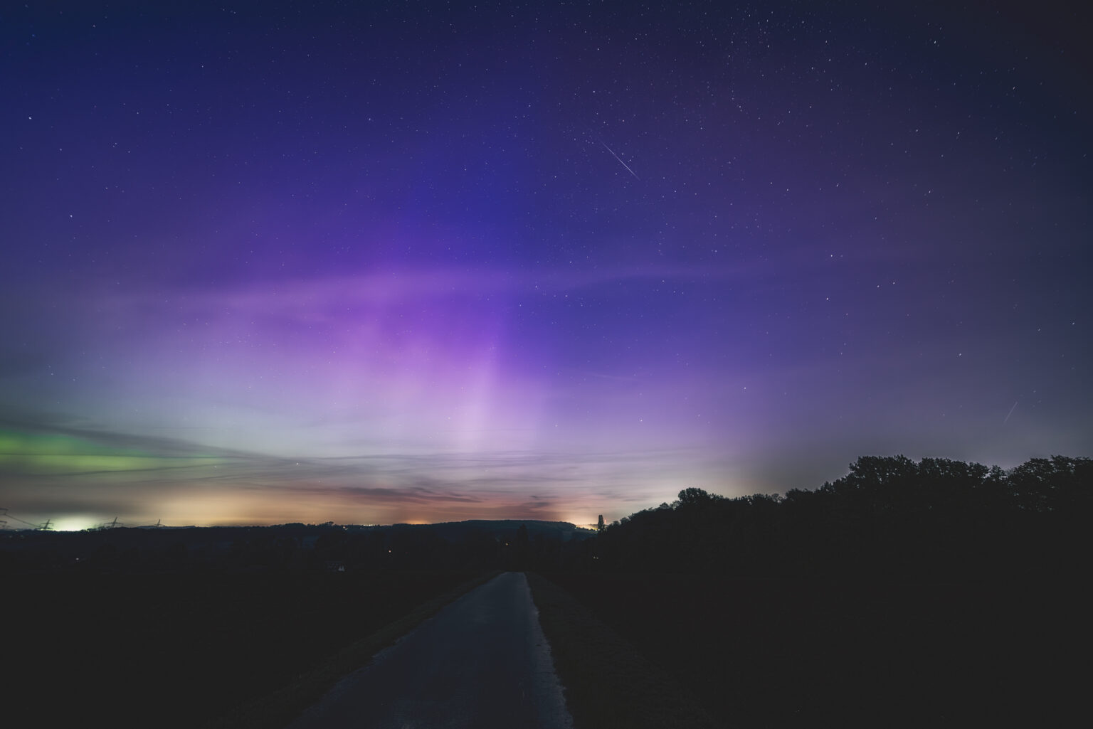 Violett-grünes Polarlicht mit Sternschnuppe über NRW-Landschaft