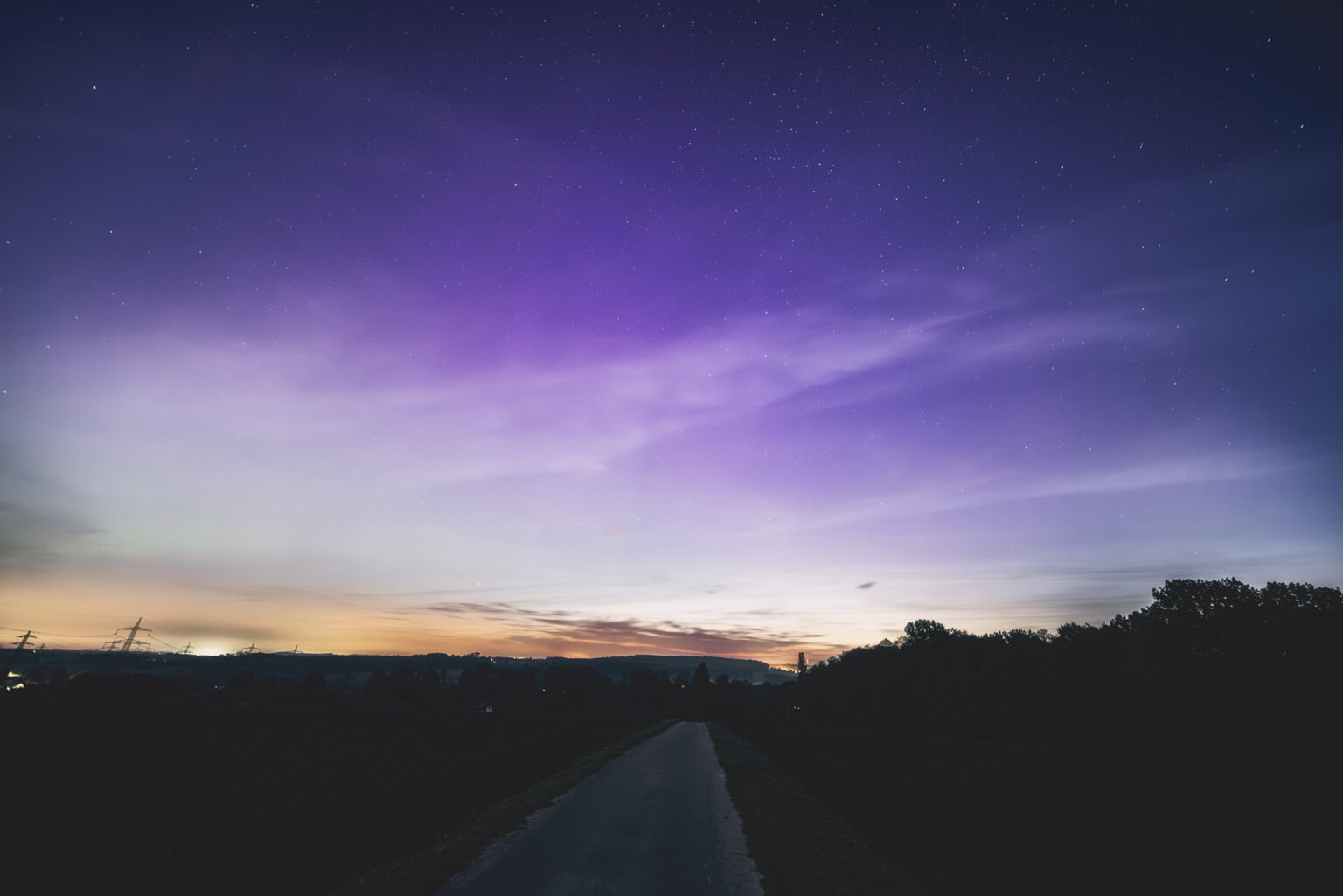 Violett-blauer Polarlichthimmel mit Schleierwolken über NRW-Landschaft
