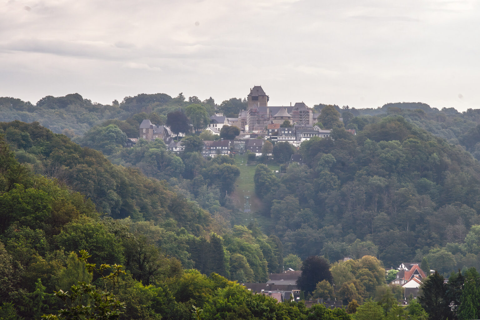 Bergisches Höhenstädtchen mit Schloss über dem bewaldeten Wuppertal aus der Ferne