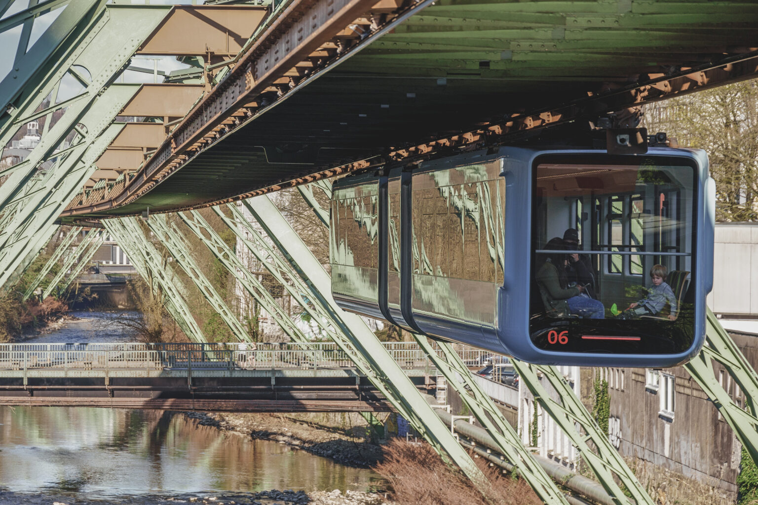 Wuppertaler Schwebebahnwagen schwebt über der Wupper am grünen Stahlgerüst