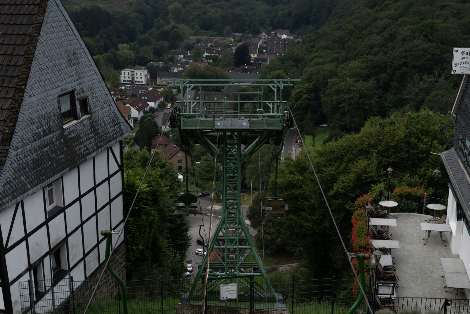 Grüne Sessellift-Konstruktion über einem Talort mit Café-Terrasse im Bergischen Land