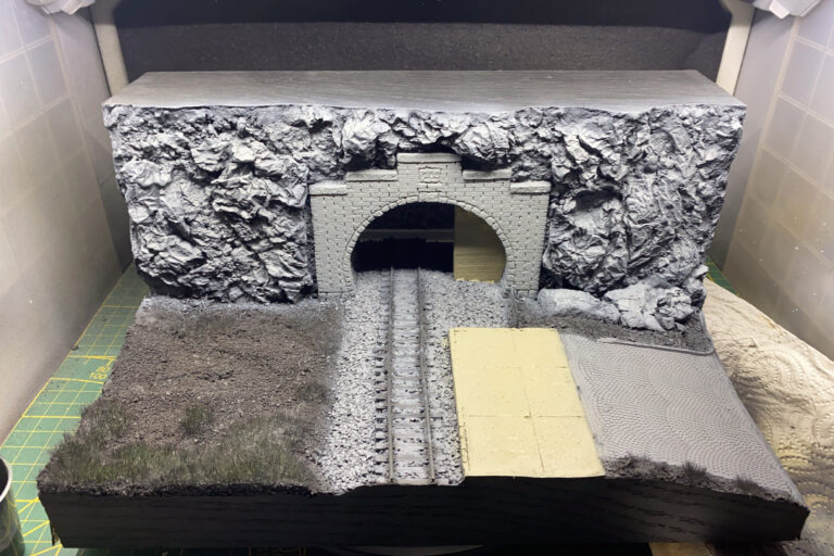 Tunnelportal-Diorama mit grauer Felswand, Schotterbett und gepflasterter Fläche