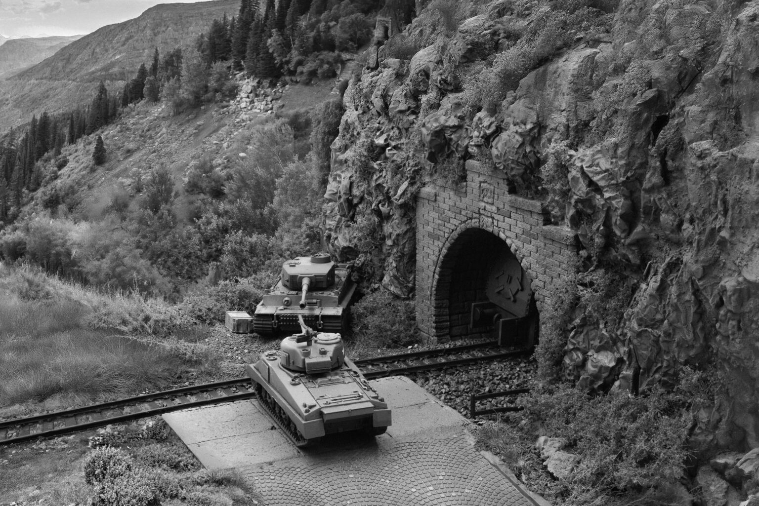 Schwarzweiße Szene des Dioramas mit zwei Panzermodellen am Tunnelportal vor Berghintergrund