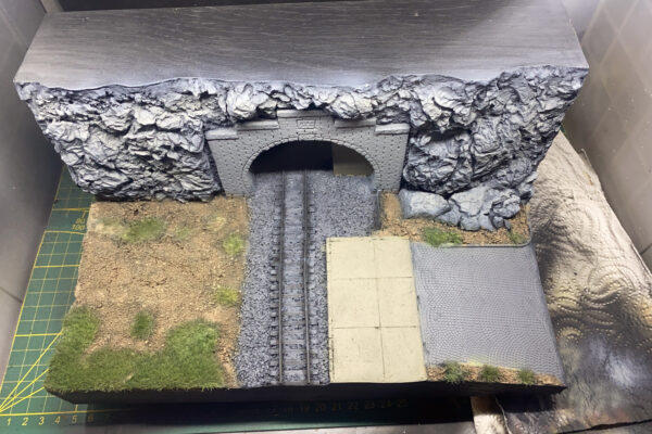 Tunnelportal-Diorama mit Felswand, Grasflächen, Schotterbett und gepflasterter Fläche