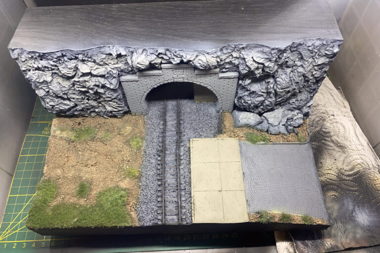 Tunnelportal-Diorama mit Felswand, Grasflächen, Schotterbett und gepflasterter Fläche