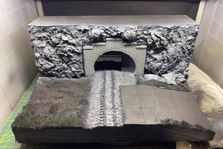 Tunnelportal-Diorama in Grautönen mit ersten Grasflächen neben dem Gleis