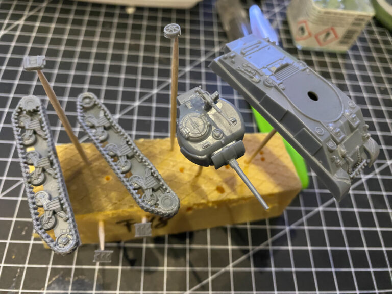 Grau grundierte Bauteile eines Tiger-Panzermodells mit Ketten und Turm auf der Schneidematte