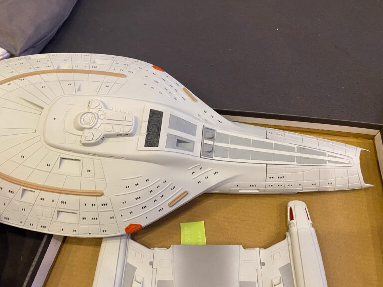 Grau lackierte Unterseite der USS-Voyager-Untertasse seitlich in der Hand über einem Karton