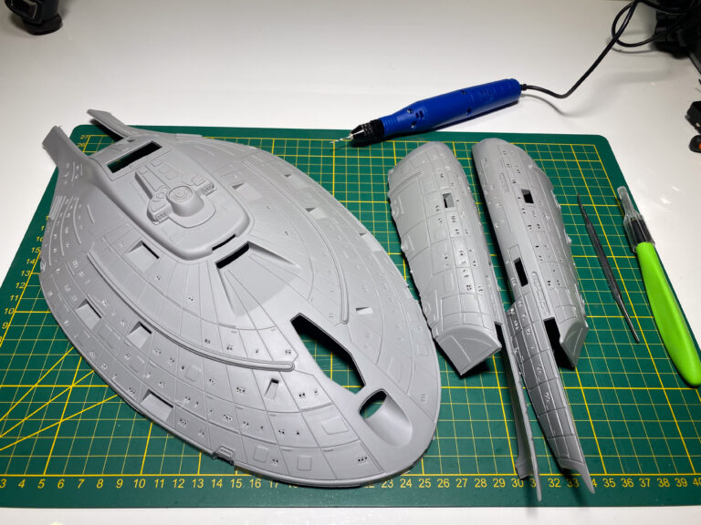 Grundierte Untertasse und Sekundärrumpf-Hälften der USS Voyager neben Werkzeug auf Schneidematte