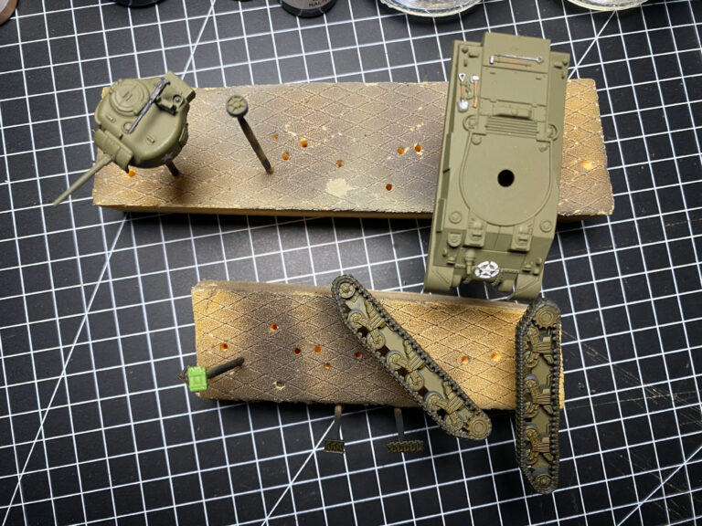 Olivgrün lackierte Bauteile von Tiger- und Sherman-Modell mit weißem Stern auf der Schneidematte
