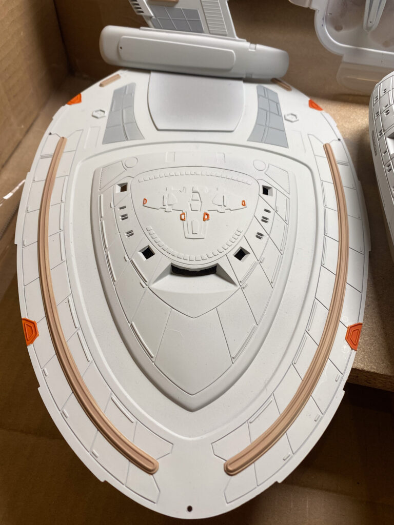 Blaue Klarteile und transparente Ständerstreben des USS-Voyager-Modells auf einer roten Schale