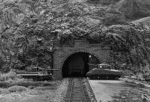 Diorama: Tiger and Sherman tanks in front of a mountain tunnel with railroad tracks.