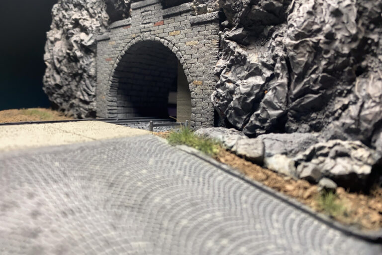 Flache Perspektive über die gepflasterte Straße zum Tunnelportal des Dioramas