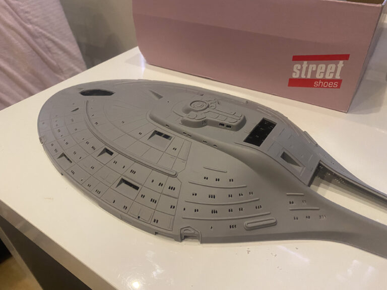 Grundierte USS-Voyager-Untertasse auf hellem Tisch mit Karton im Hintergrund