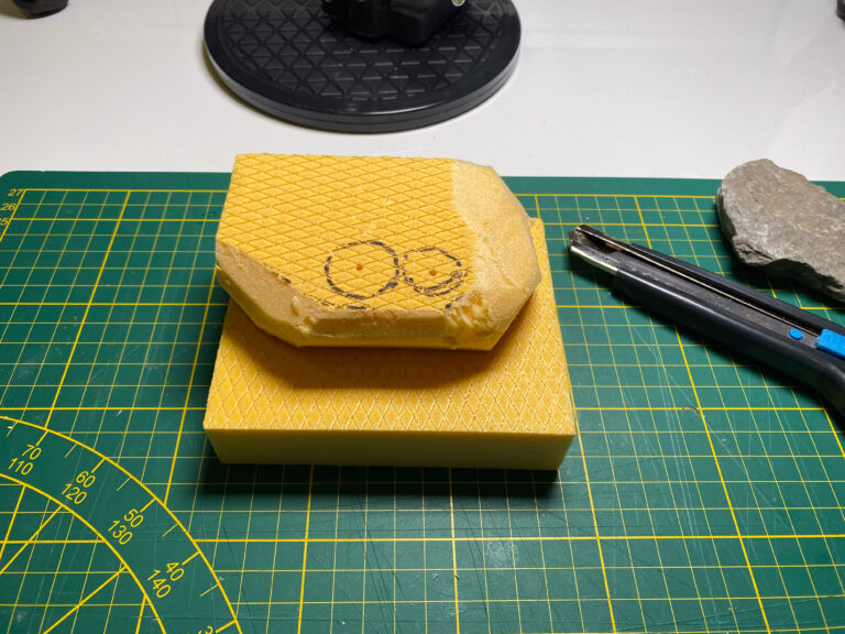 Gelbe Schaumstoff-Grundplatte für ein Mini-Diorama wird mit einem Messer zugeschnitten