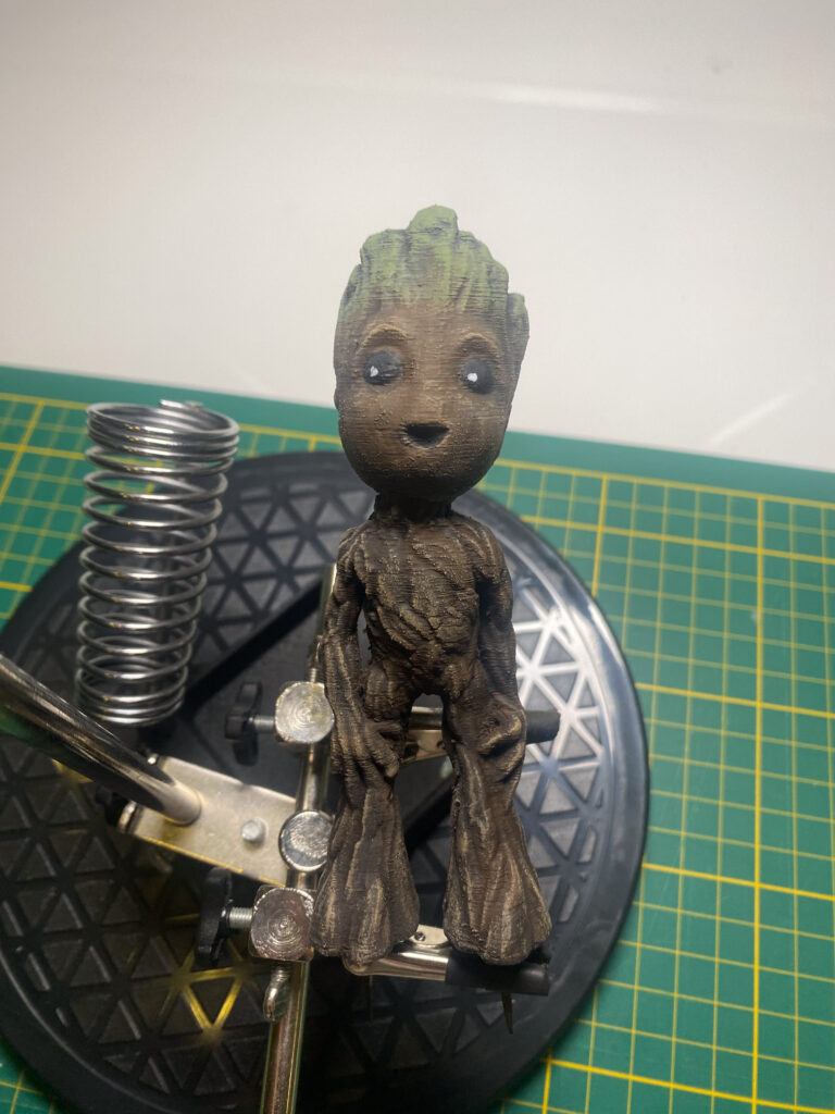 Fertig bemalte Baby-Groot-Figur mit grünem Laub am Kopf und brauner Rinde auf dem Drehteller