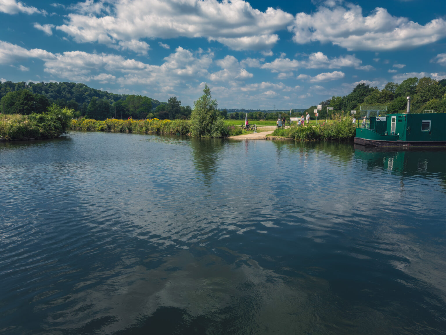 Ruhr mit grünem Hausboot am rechten Ufer und Feldern unter sommerlichem Himmel