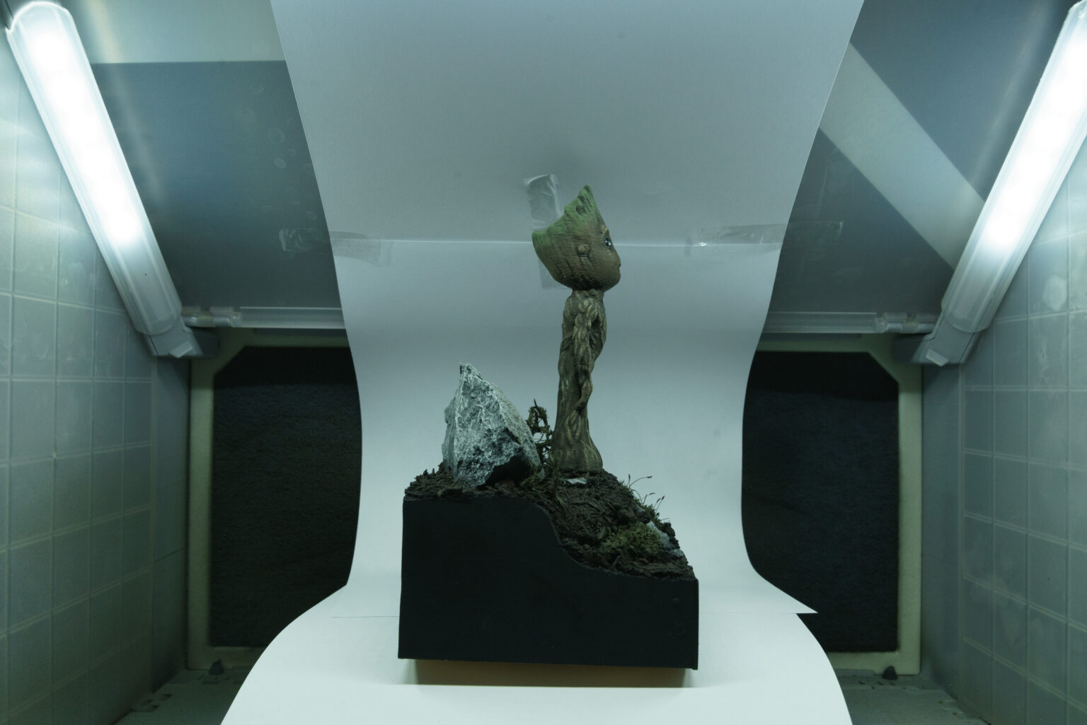 Fertige Baby-Groot-Figur auf einem kleinen Diorama-Sockel mit Stein und Moos im Lichtzelt