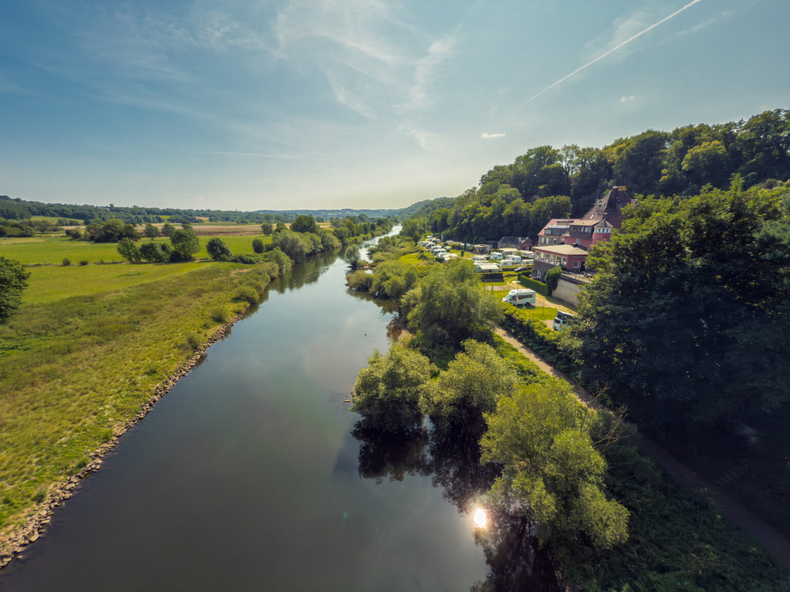 Blick über das Ruhrtal mit Fluss, Campingplatz und einem Gebäude am bewaldeten Hang