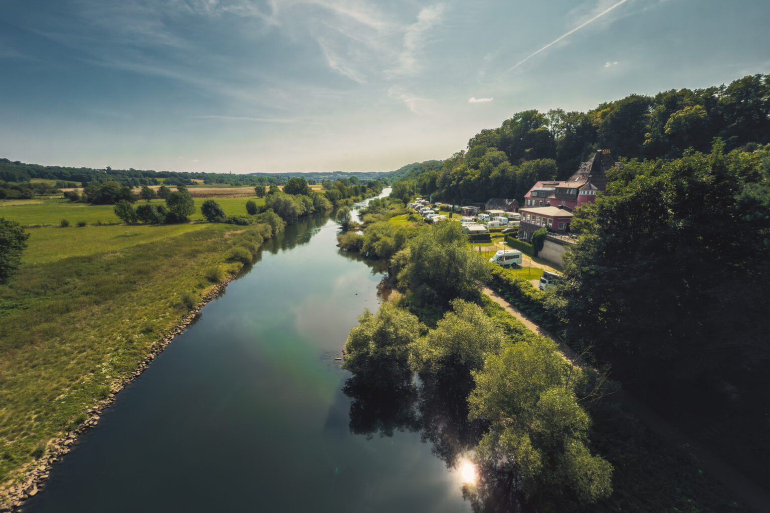 Ruhrtal mit Fluss, Campingplatz und Hanggebäude unter weitem Sommerhimmel