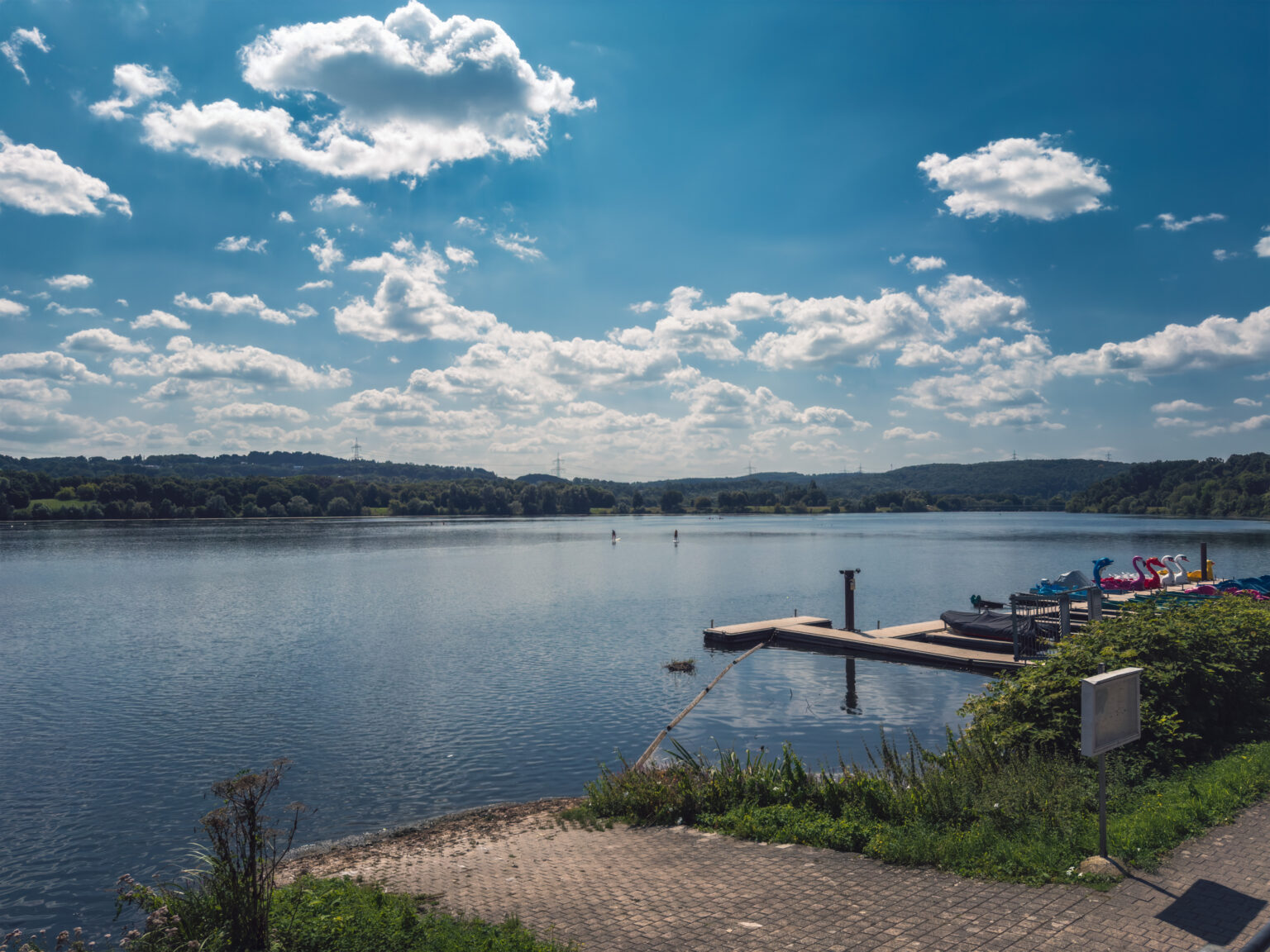 Stausee im Ruhrtal mit Tretboot-Steg und Wolkenhimmel über bewaldeten Ufern