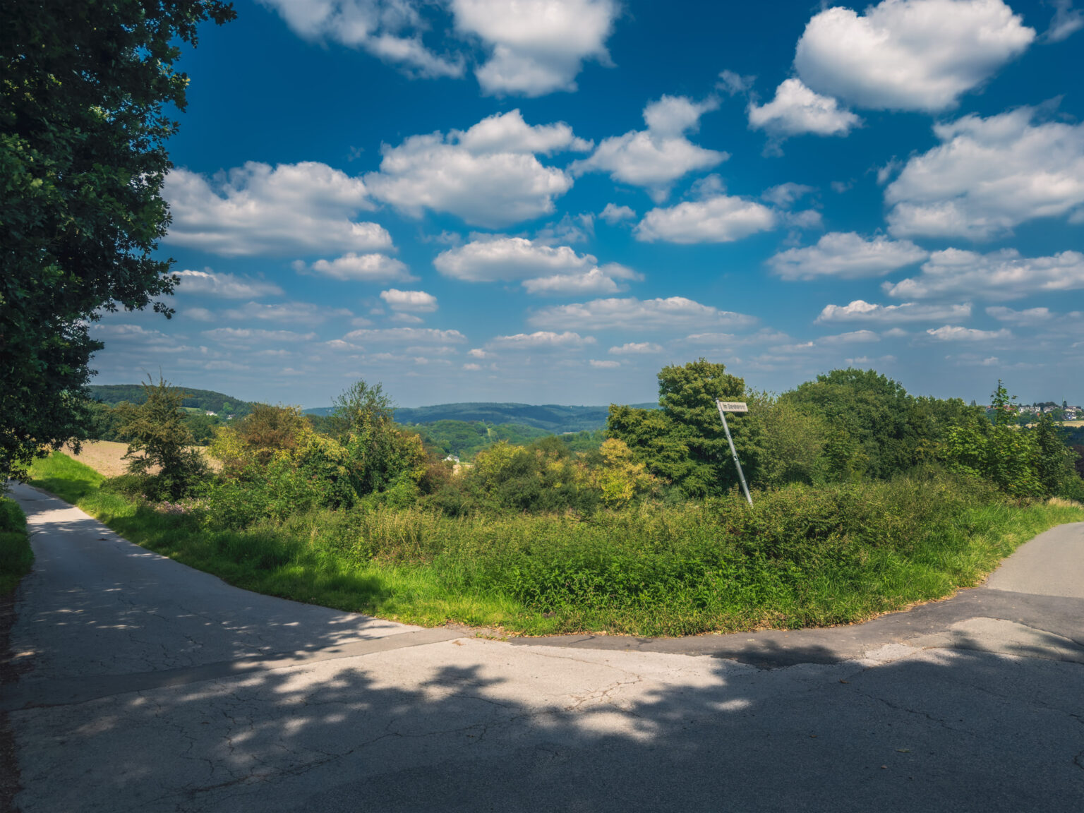 Feldweg-Kreuzung mit Panoramablick über das Bergische Land und einem Wegweiser