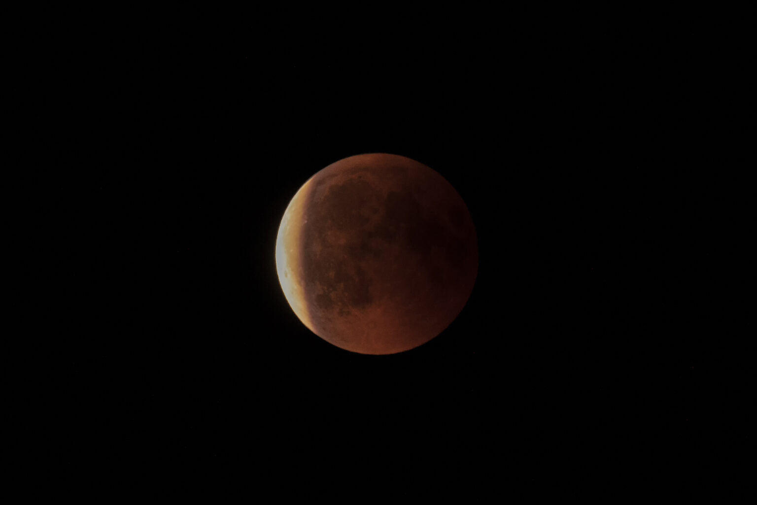 Partielle Mondfinsternis mit rötlich gefärbtem Mond am Nachthimmel.