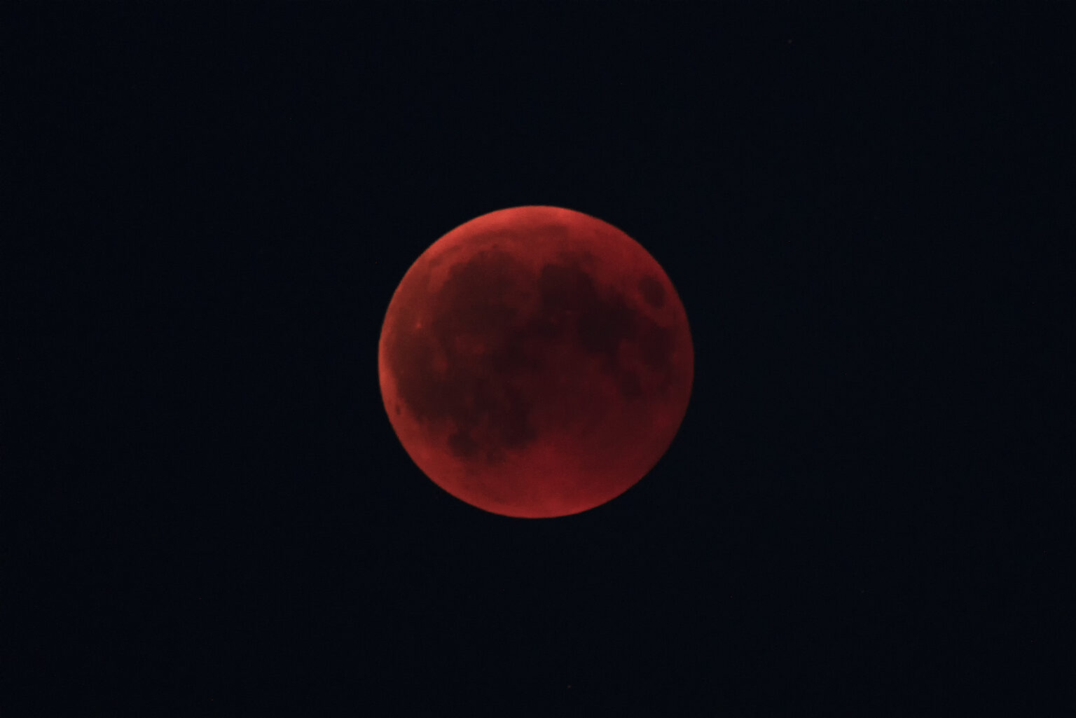 Ein roter Blutmond am dunklen Nachthimmel.