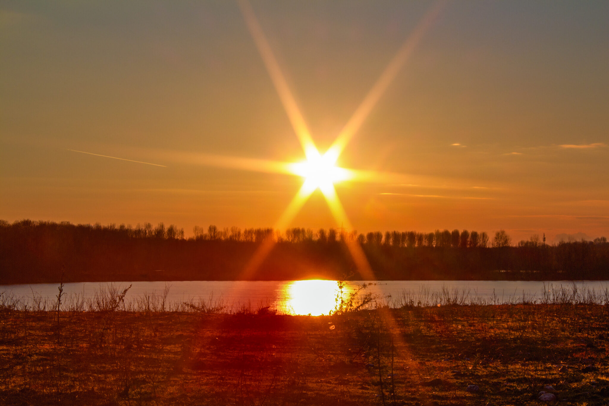 Die strahlende Abendsonne versinkt über dem Elbsee.