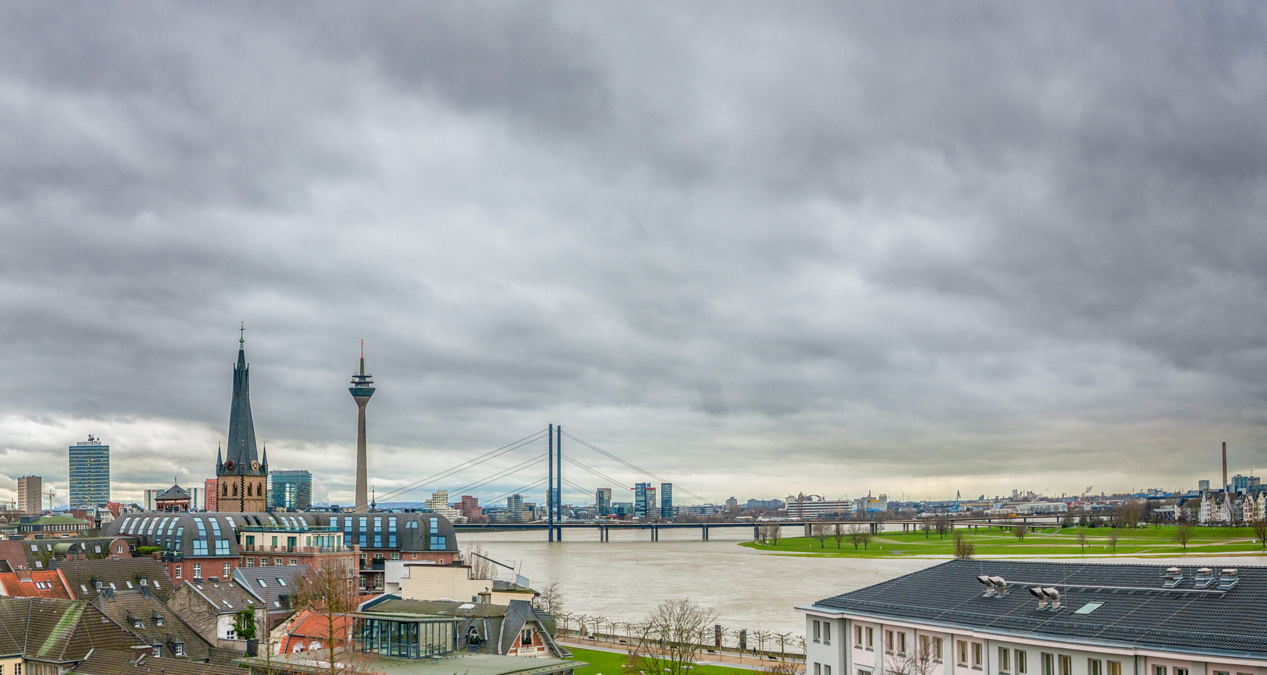 View from the Kunstakademie over the rooftops of the old town to St. Lambertus, the Rheinturm, the Rhine and the Rheinknie bridge under a grey sky