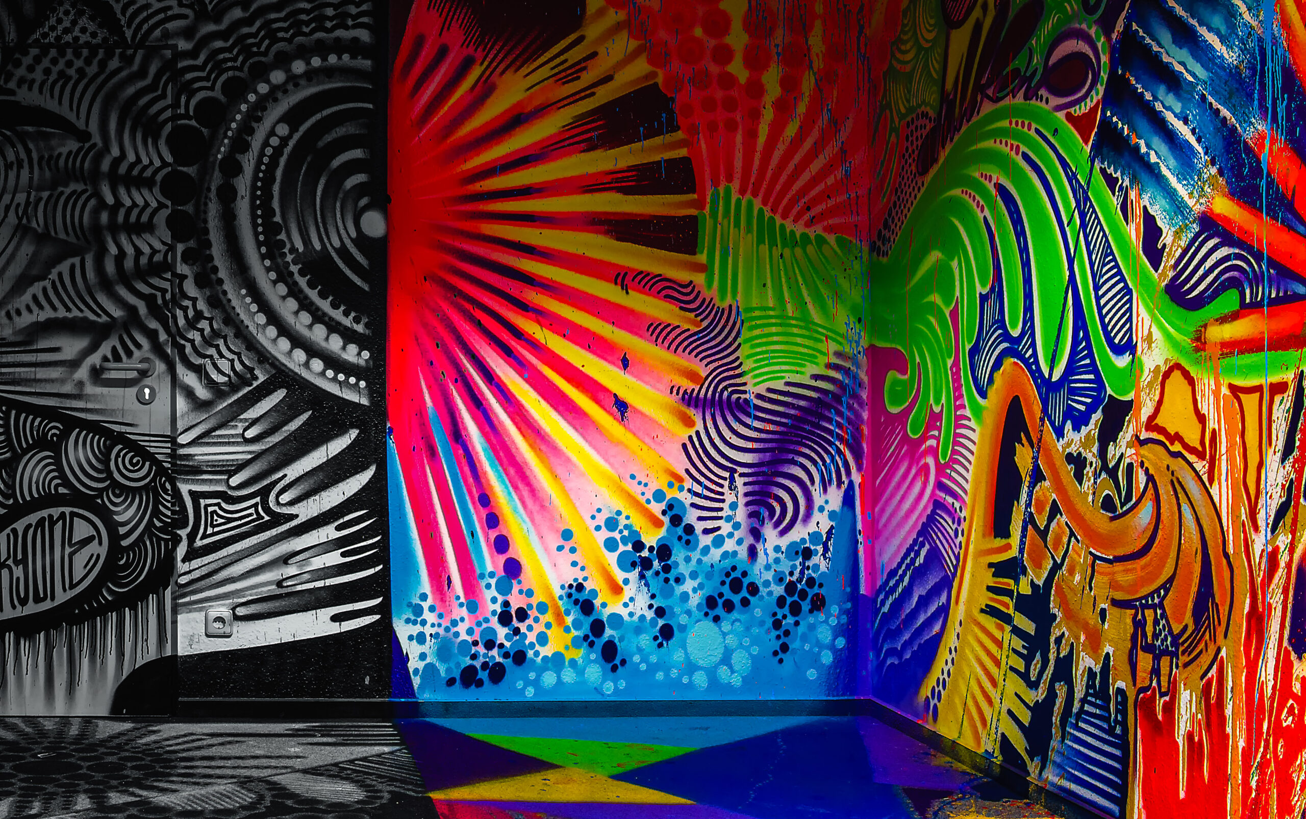 A fully painted room in loud colours, a black-and-white wall with ornaments on the left