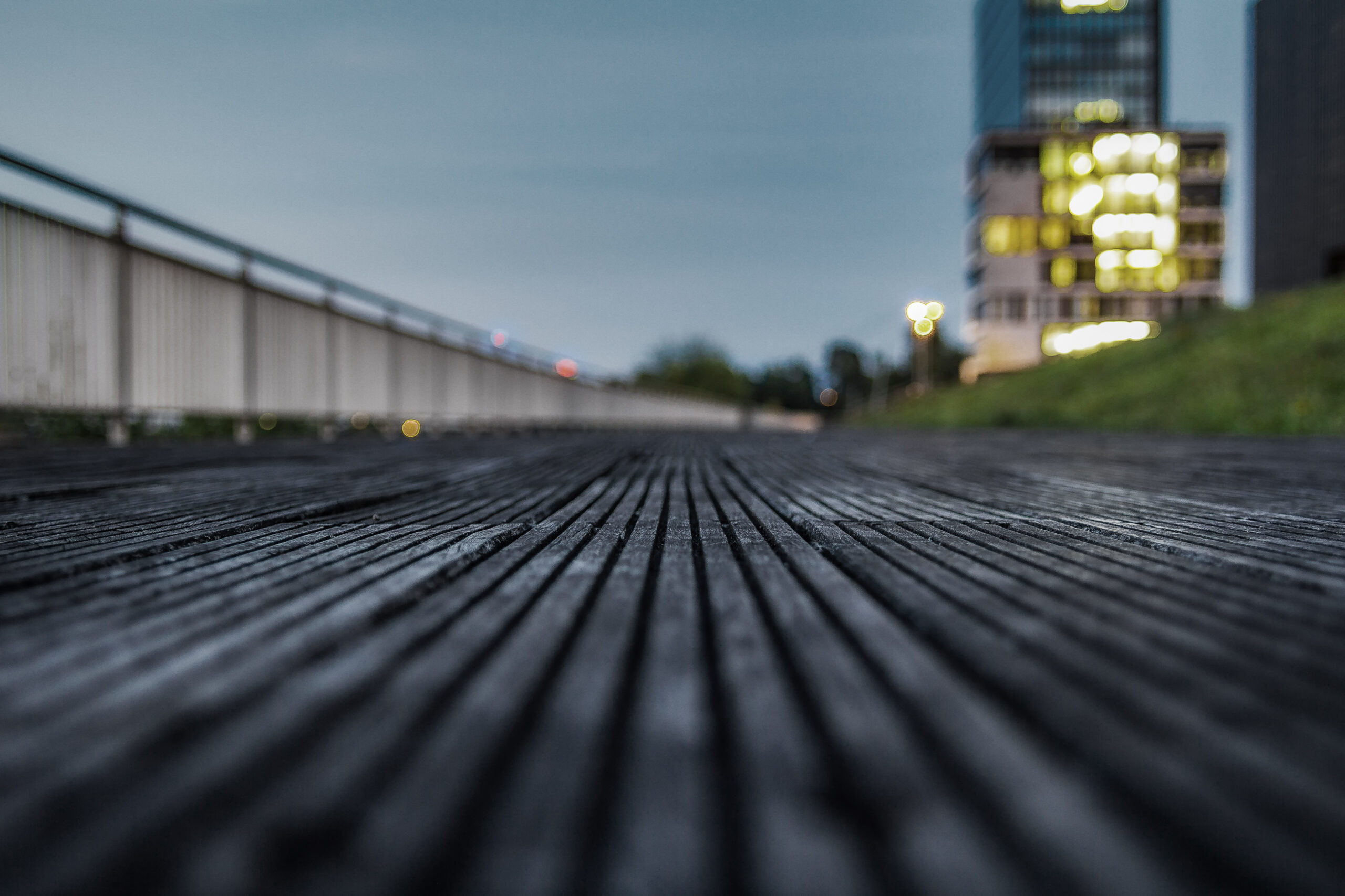 Wooden jetty in the Medienhafen from a low angle, a lit high-rise out of focus in the background