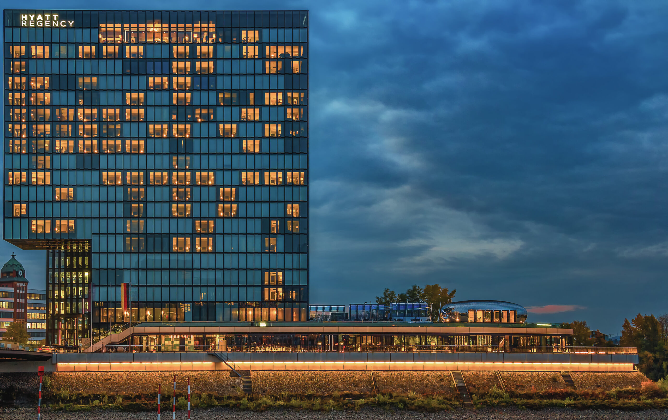 The Hyatt hotel in the Medienhafen in the evening, lit windows under a blue sky