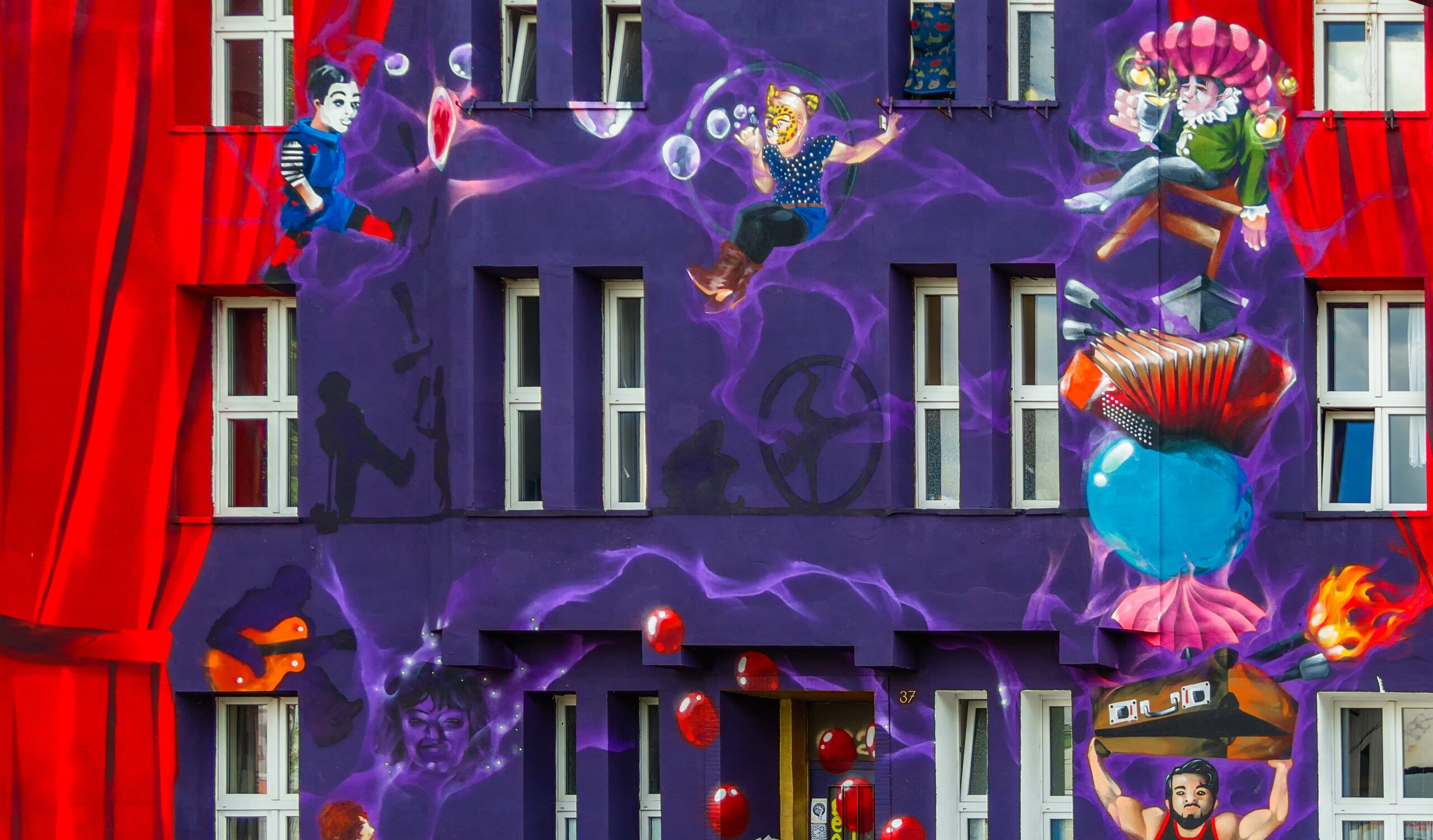 Purple house facade with painted red curtains and flying figures between the windows