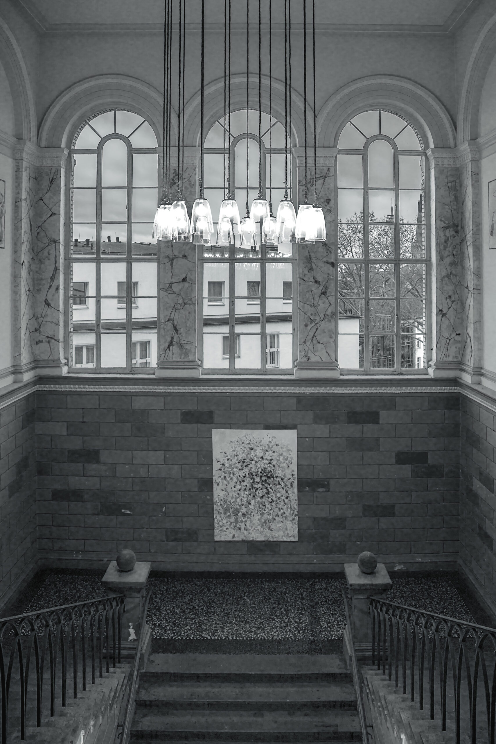 Stairwell of the Kunstakademie in black and white with arched windows, chandelier and curved railings
